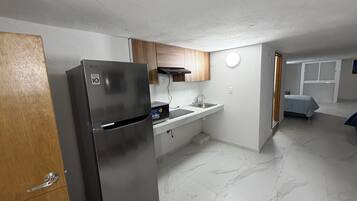 Una cocina compacta con un refrigerador de acero inoxidable, un microondas y un lavamanos.