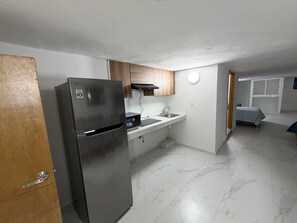Una cocina compacta con un refrigerador de acero inoxidable, un microondas y un lavamanos.