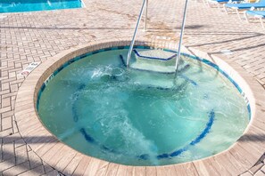 Un jacuzzi rond, bordé de carreaux, entouré d’une terrasse en briques.