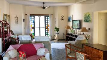 A living room with a sofa, chairs, a coffee table, a TV, and a ceiling fan.