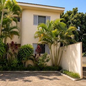 A two-story building with a flat roof, surrounded by lush greenery and palm trees. - Pousada dos Reis Ibirá (Ibira)