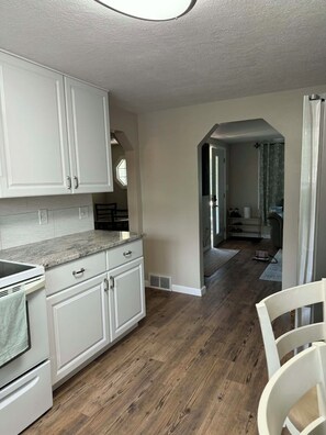 A kitchen with white cabinets, a granite countertop, and a wood floor.