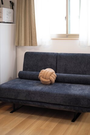 Ein graues Sofa mit einer strukturierten Kissen auf einem Holzboden.