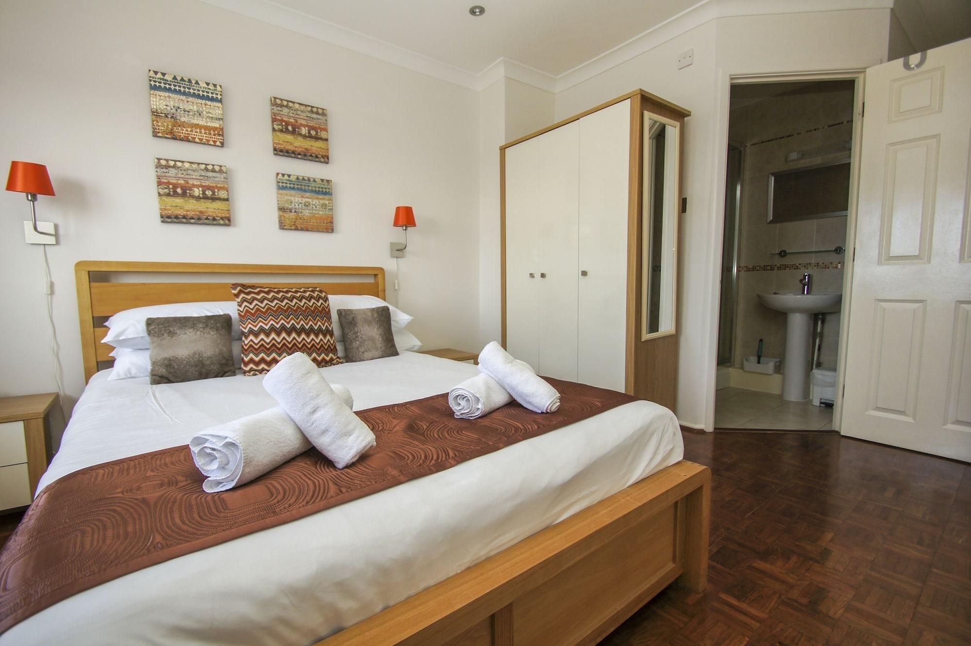 A hotel room with a bed, a wardrobe, a bathroom, and wall art.