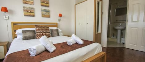 A hotel room with a bed, a wardrobe, a bathroom, and wall art.