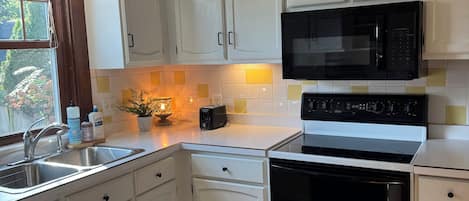 A kitchen with white cabinets, a microwave, an oven, and a sink.