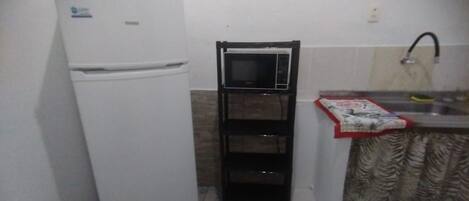 A compact kitchen with a white refrigerator, a black microwave, and a sink with a faucet.