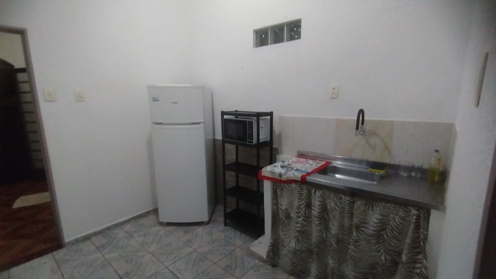 Una cocina compacta con refrigerador, microondas y pileta.