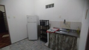 A compact kitchen with a refrigerator, a microwave, and a sink.