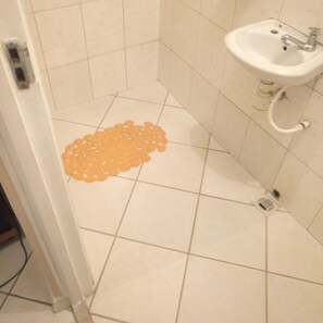 A bathroom with a sink, a drain, and a patterned mat on the floor. - Blue Bay Hotel (Nakuru)