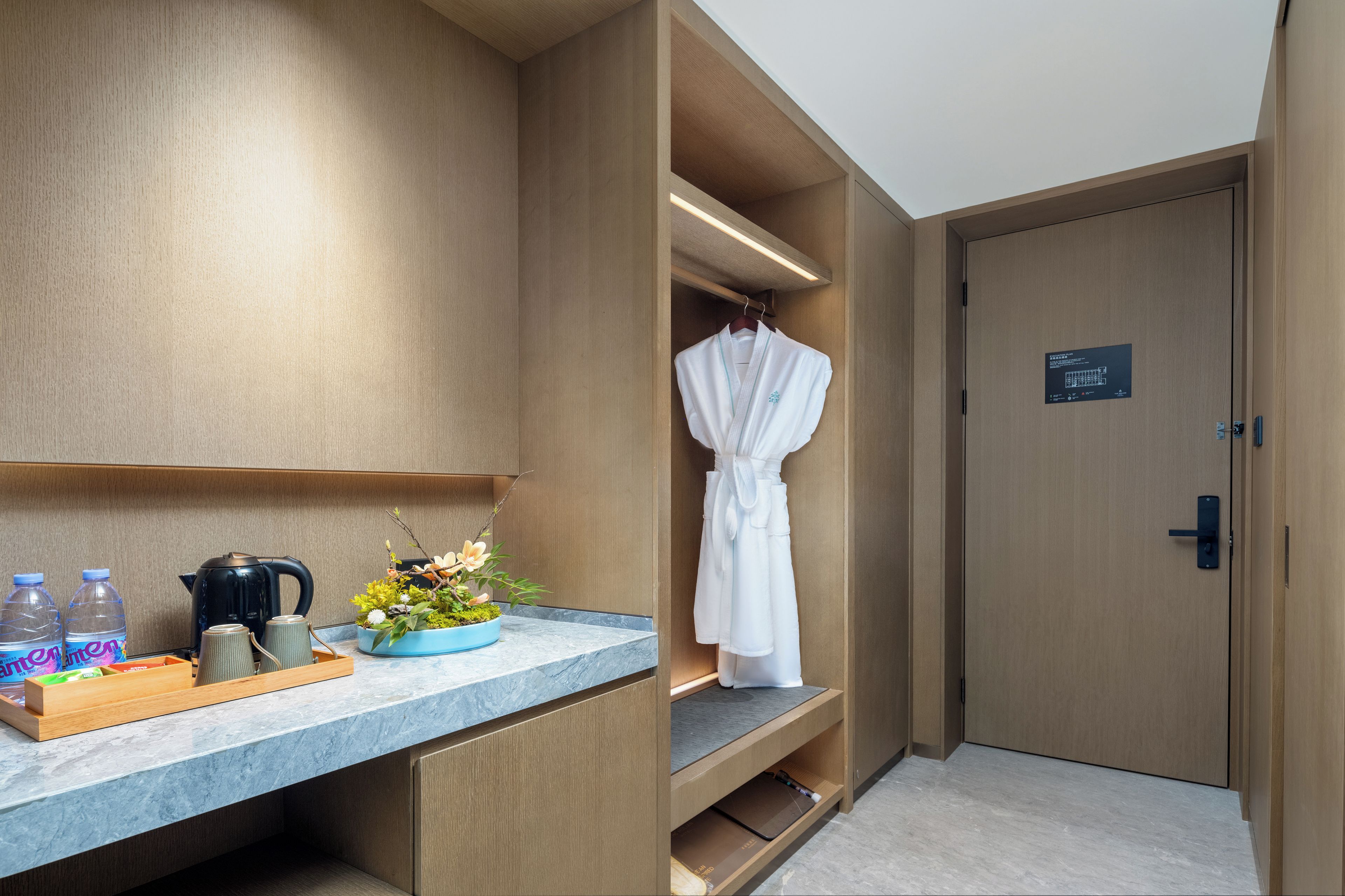 Ein Hotelbad mit einem Holzbadezimmer-Möbel, einem Bademantel auf einem Gestell und einer kleinen Ablage für Toilettenartikel.