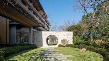 Un edificio moderno con un arco de piedra, un césped cuidado y un cielo despejado.