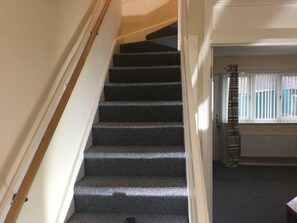 A staircase with a dark patterned carpet leading to a landing.