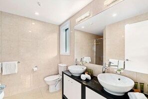 Ein modernes Badezimmer mit großem Spiegel, zwei Waschbecken, Toilette und Dusche.