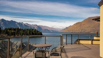 A terrace with a table and chairs overlooking a lake and mountains.