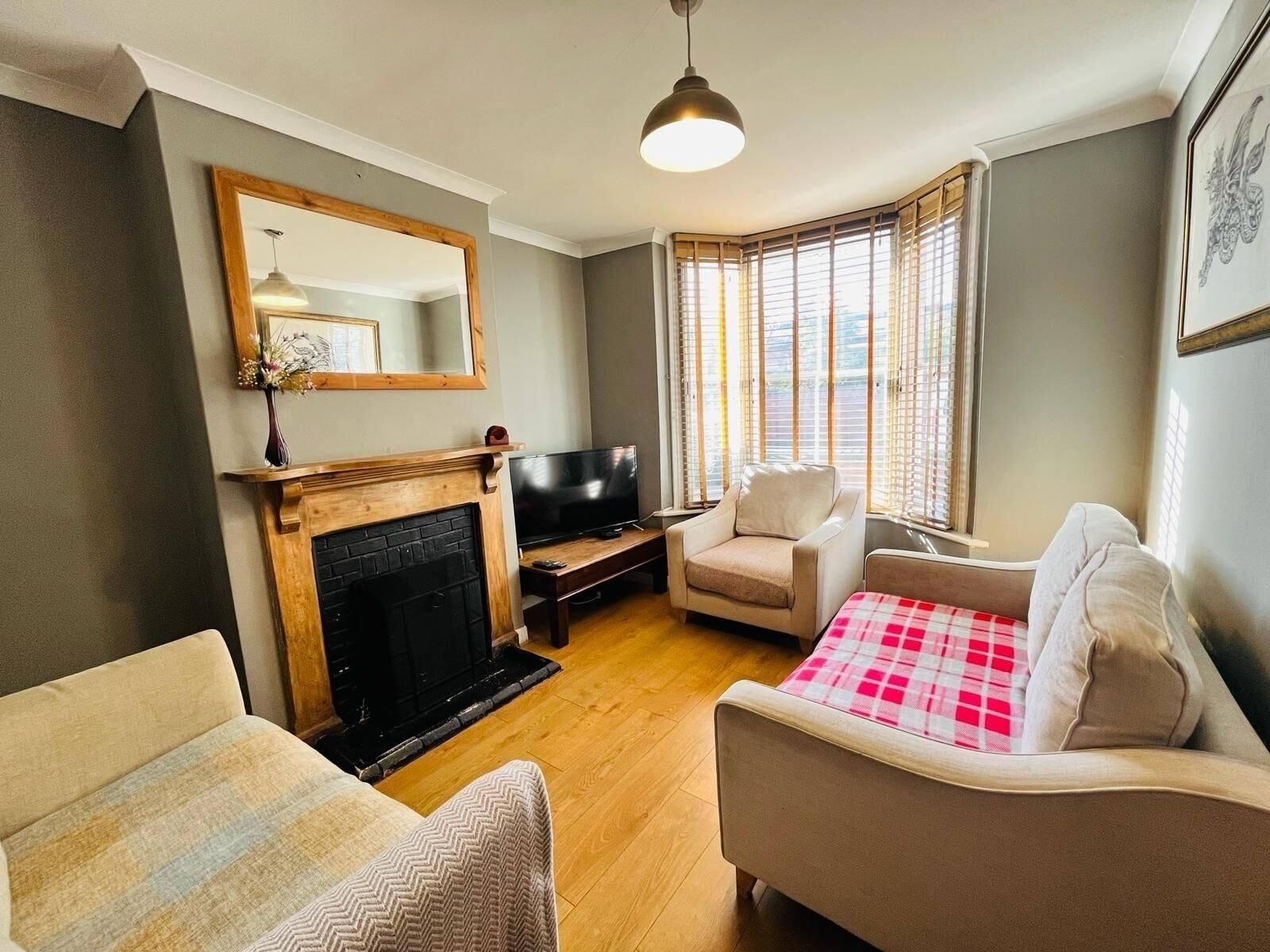 A living room with a fireplace, a television, and two armchairs.