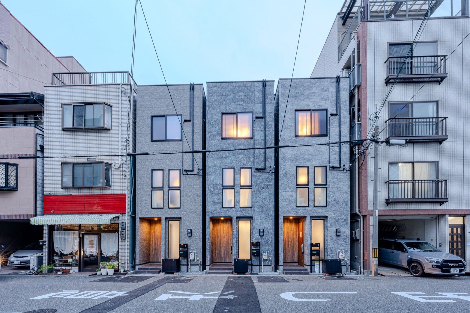 A row of modern buildings with a flat facade, multiple windows, and a visible entrance with a door.