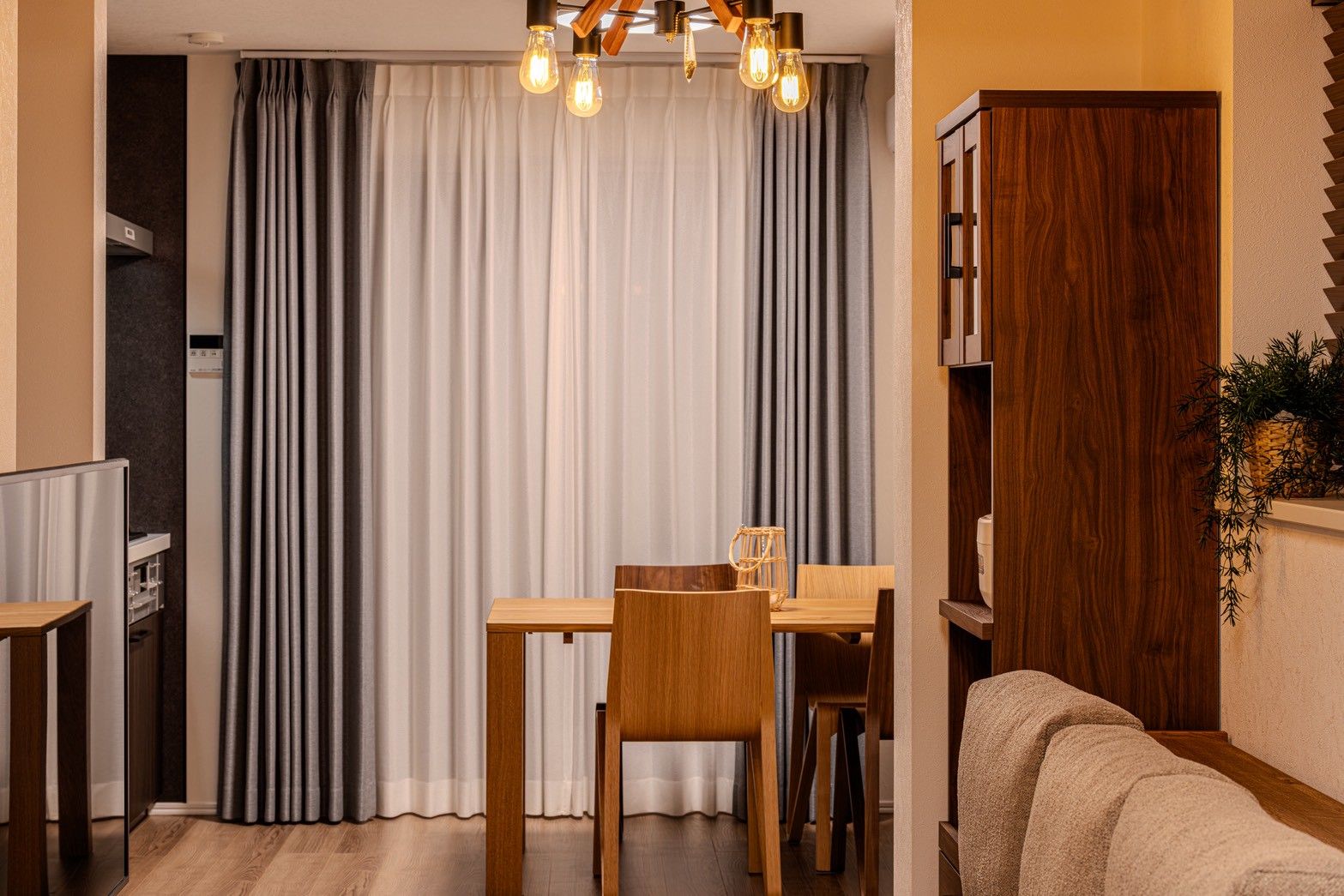A dining area with a wooden table and chairs, a chandelier, and a sofa.