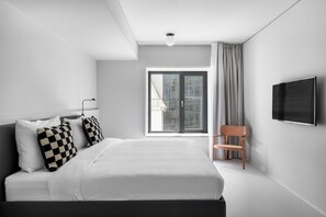 A modern hotel room with a large bed, a television mounted on the wall, and a window with curtains. - Stilwerk Hotel Kantgaragen (Berlin)