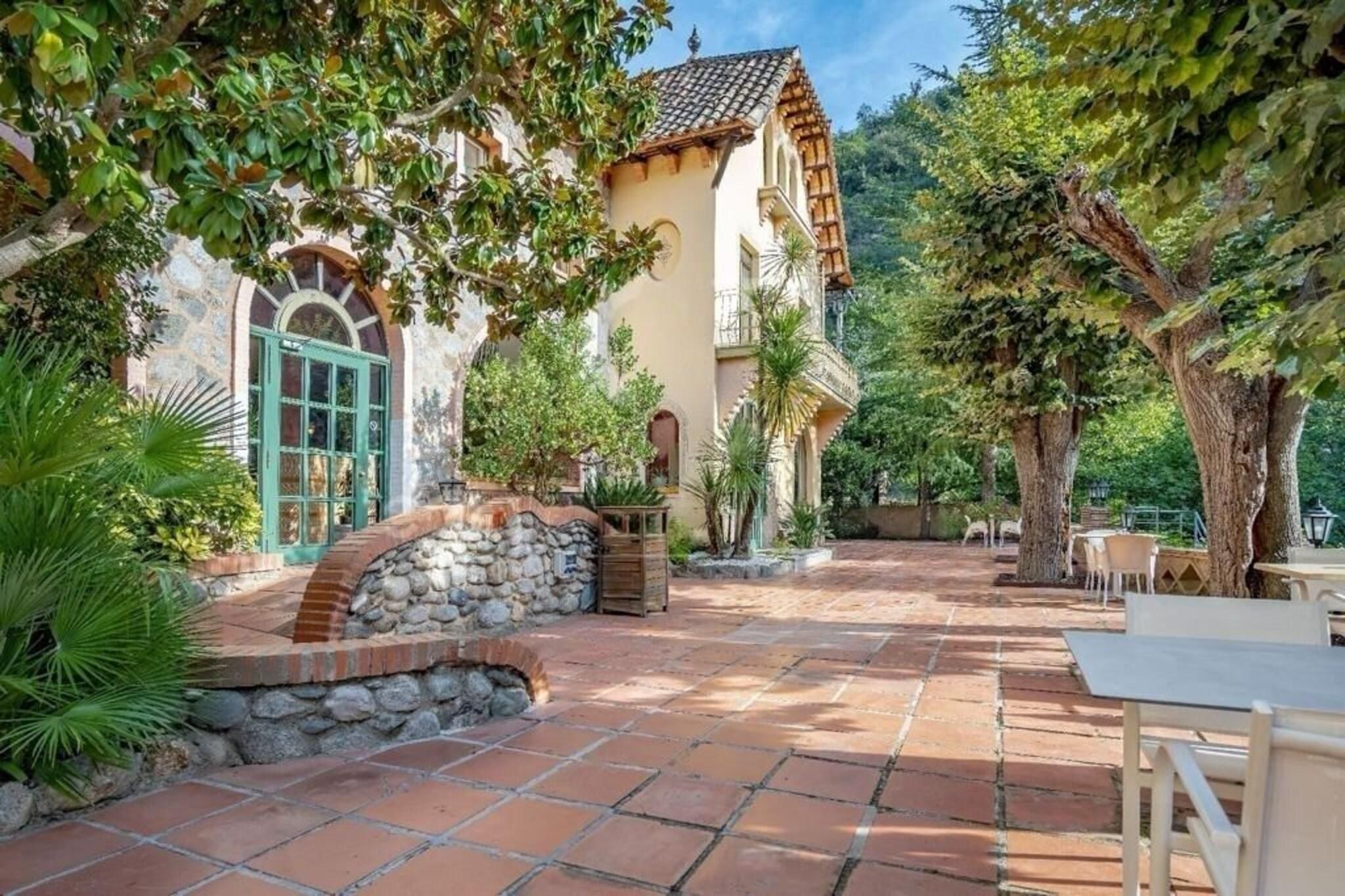 A courtyard with a stone wall, a wooden bench, and a table.