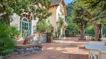 A courtyard with a stone wall, a wooden bench, and a table.