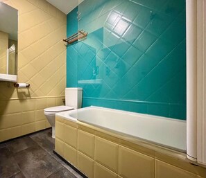 Une salle de bain avec des toilettes, une baignoire et un miroir.