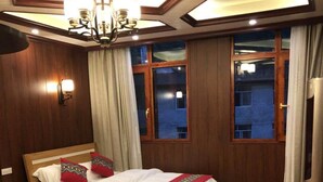 A hotel room with two beds, a chandelier, wooden walls, and large windows. - Li Sen Hotel Resort (Enshi)