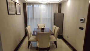 A hotel room with a dining table, six chairs, a large window with curtains, a door, and a thermostat on the wall. - Li Sen Hotel Resort (Enshi)