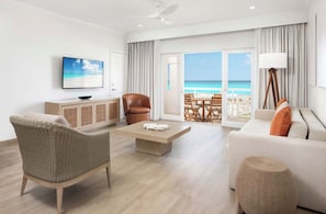 A hotel room with a balcony, a television, a sofa, a chair, and a coffee table.