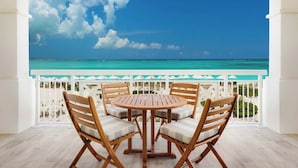 A balcony with a view of the ocean, wooden chairs, and a white railing. - Oceanfront 2BR on Grace Bay at Alexandra Resort 2nd fl 1,384 Sq Ft (The Bight Settlement)