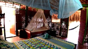 A room with a bed under a mosquito net, a small table, and a fan. - Las Palmeras (Cartagena)