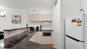 A modern kitchen with a built-in microwave, a coffee maker, and a refrigerator. - Central Cairns City Stay with Pool | The Base Inn (Cairns City)
