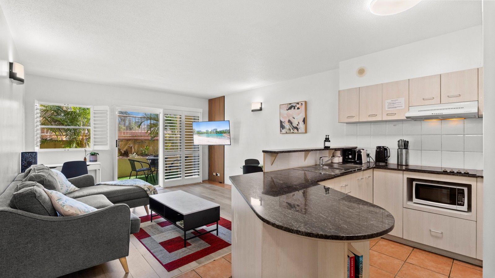 A compact living space with a kitchenette, a sofa, a coffee table, and a TV.
