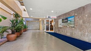 A hotel reception area with a reception desk, a sign for the reception, and a view of the sea on the wall. - Central Cairns City Stay with Pool | The Base Inn (Cairns City)