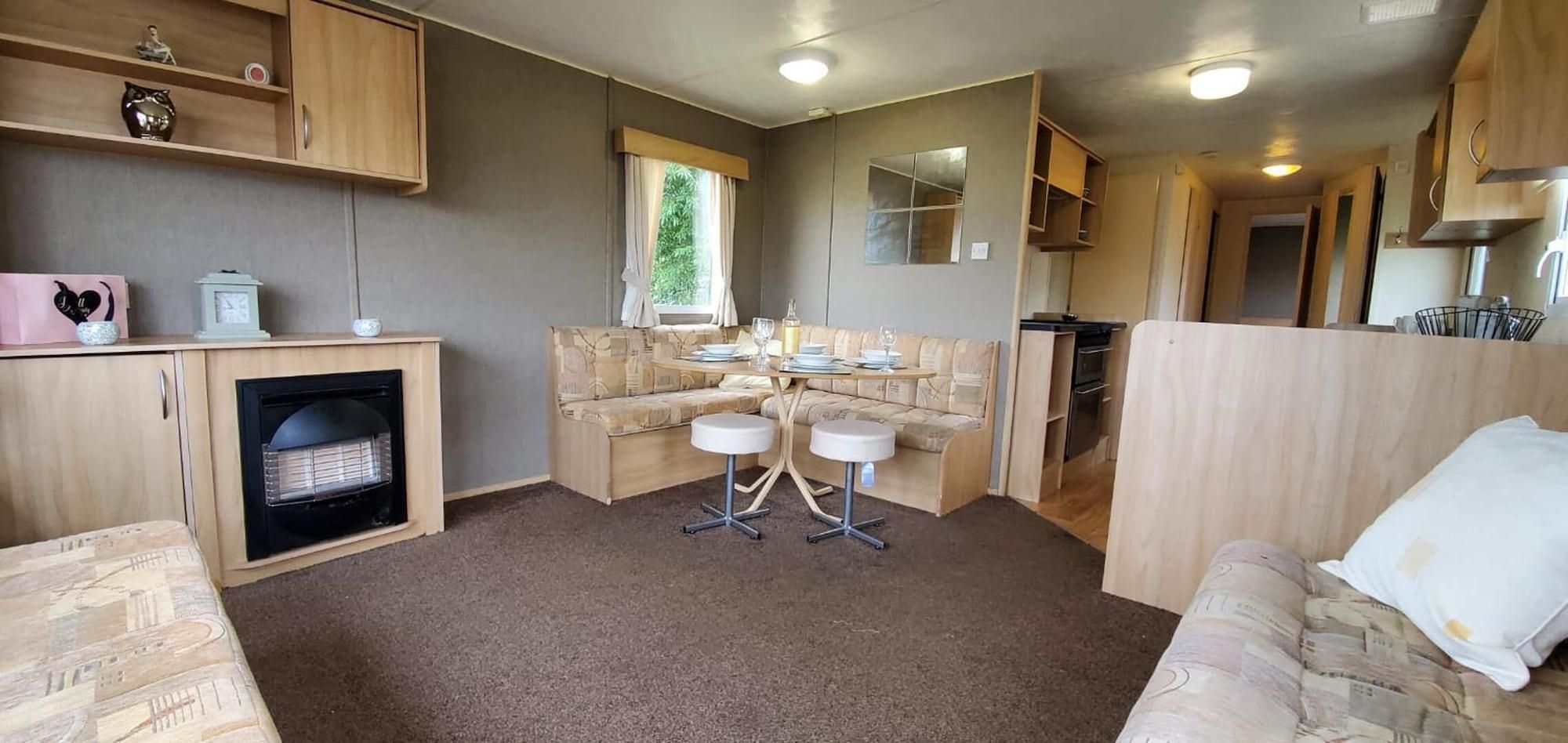 A compact living space with a kitchenette, a sofa, a dining table, and a fireplace.