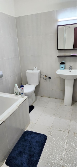 Un baño con inodoro, lavabo y espejo sobre él.