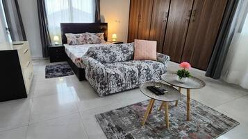 Un dormitorio moderno con cama, mesitas de noche, un pequeño sofá, una mesa de centro y un armario.