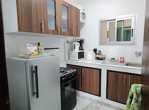 Una cocina con armarios de madera, un refrigerador de acero inoxidable, una estufa a gas y un microondas.