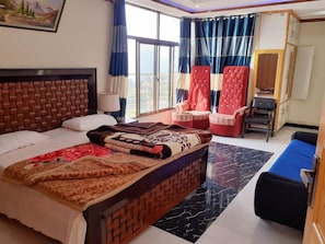 A hotel room with a bed, a chair, a sofa, and a large window. - Bhurban Apartments (Bhurban)