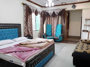 A bedroom with a bed, two chairs, a sofa, and curtains. - Bhurban Apartments (Bhurban)