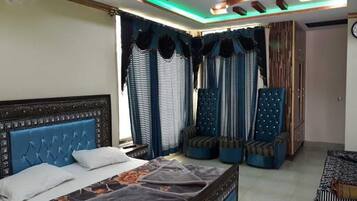 A bedroom with a bed, a seating area, and a window with curtains.