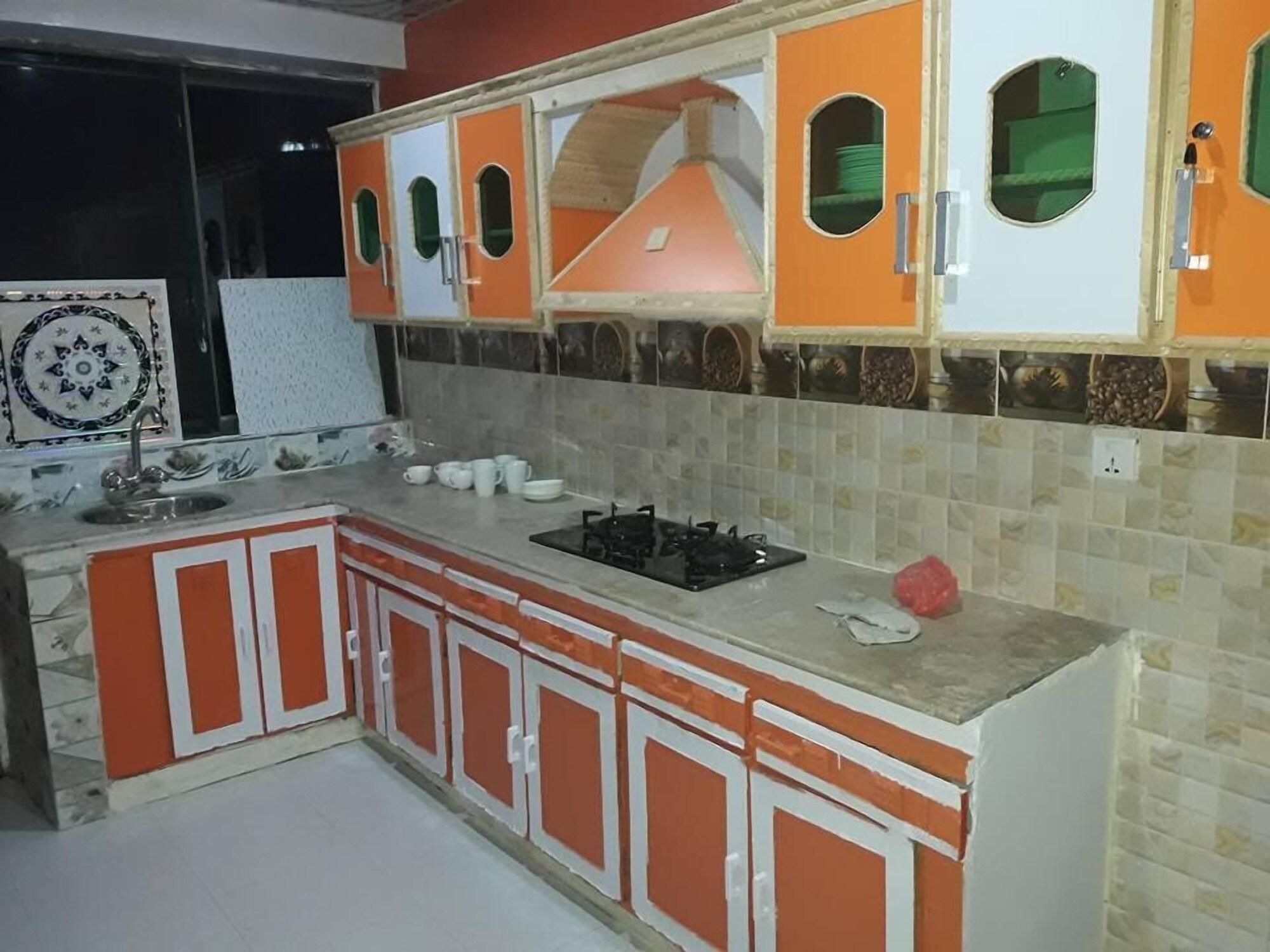 A kitchen with orange cabinets, a gas stove, and a tiled backsplash.