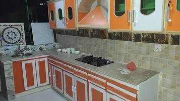 A kitchen with orange cabinets, a gas stove, and a tiled backsplash.