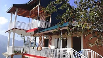 A multi-story building with balconies, a staircase, and a view of the mountains.
