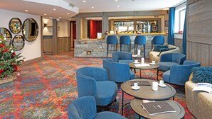 A hotel lobby with a bar area, multiple seating options, and a stone fireplace. - L'aigle Du Montana (Tignes)