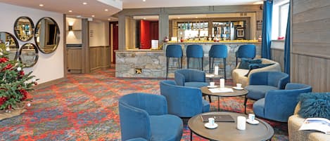 A hotel lobby with a bar area, multiple seating options, and a stone fireplace.