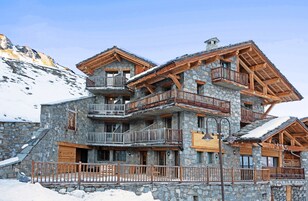 Un edificio de varios pisos de piedra con balcones de madera y fachada de piedra.