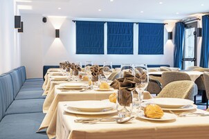 Una larga mesa de comedor con platos, vasos y servilletas, con un sofá y sillas al fondo.
