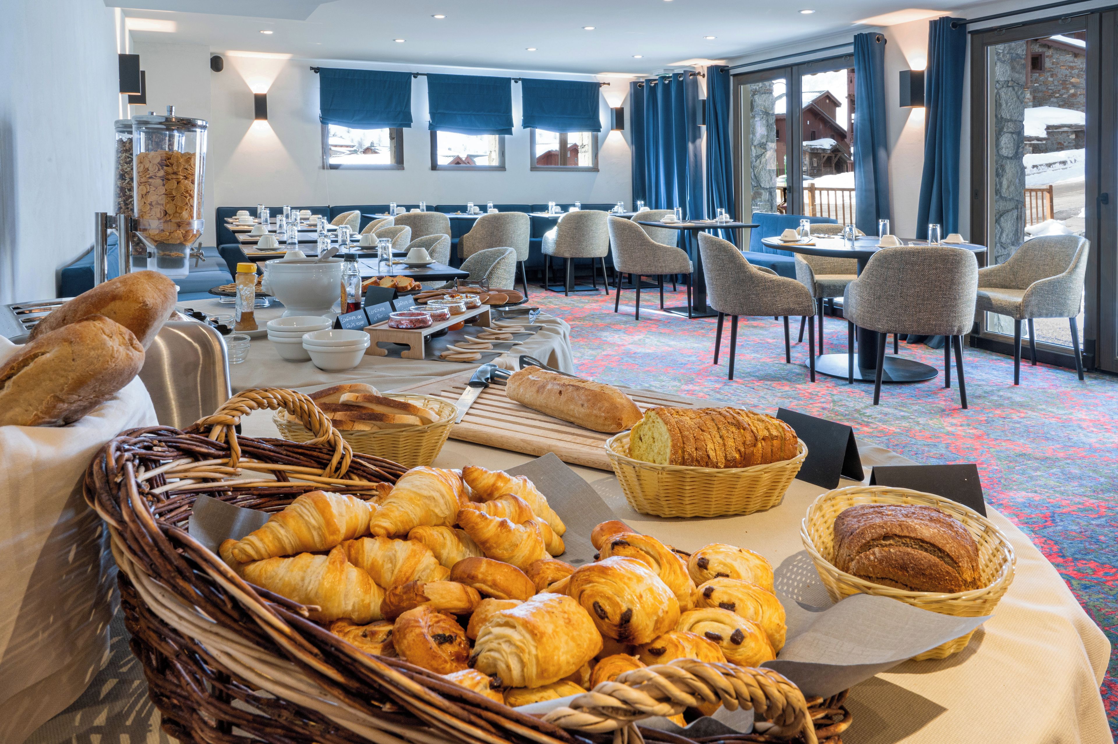 A breakfast buffet with bread, pastries, and beverages.