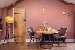 Ein Essbereich mit Holztür, einem runden Tisch mit Stühlen, einer Stehlampe und hängenden Leuchten.